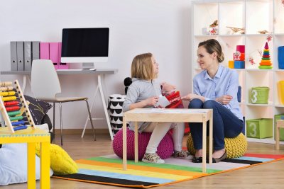 child with pedagogue during the session of play therapy